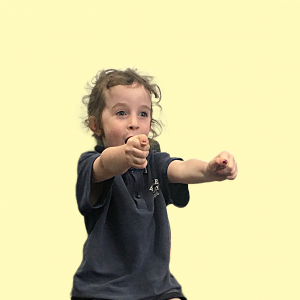 Primary School aged child in school uniform holds dramatic pose. Child's arms are outstretched and face has a surprised look.